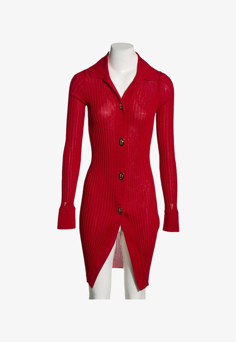 Cardigan long rouge en maille côtelée avec col et quatre boutons, porté sur un mannequin blanc, avec manches longues et fente avant à l'ourlet.