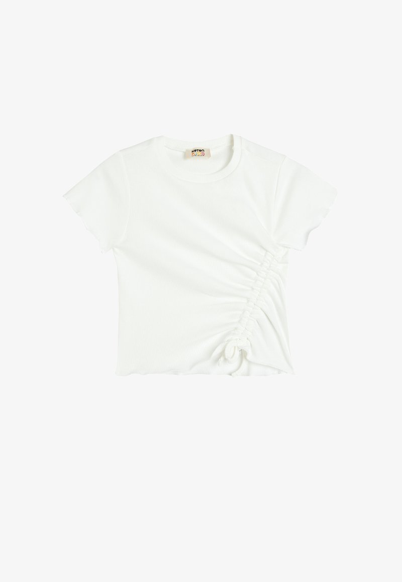 Camiseta de algodón blanco con mangas cortas. Presenta fruncidos laterales con detalle de cordón, textura acanalada y un escote redondeado.