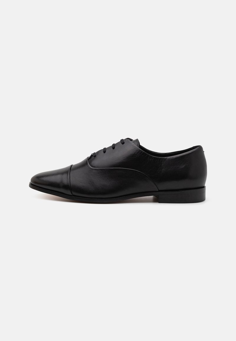Zapato de vestir de cuero negro con puntera afilada, costuras curvas decorativas, seis ojales y un tacón bajo apilado. Textura suave en general.