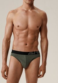 Zielone slipy wykonane z miękkiego materiału z czarnym pasem w talii, na którym znajduje się biały napis. Projekt obejmuje nisko cięty nogawkę i dopasowany krój.