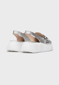 Zapatos slingback de cuero plateado con un upper texturizado, que cuentan con una amplia suela de plataforma blanca y un detalle decorativo de hebilla.