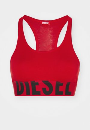 Red sports bra with racerback design, featuring a black band with "DIESEL" printed. Made from stretchy fabric with a smooth texture.