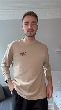 T-shirt de manga longa bege claro, com um gráfico de cavalos e uma figura. O material parece suave, com um corte descontraído e decote canelado.