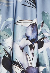 Blue fabric with large, detailed floral patterns in shades of blue, white, black, and green, featuring abstract leaves and petals.