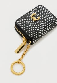 Μαύρο και λευκό μοτίβο τσαντάκι με φερμουάρ, κατασκευασμένο από υλικό με υφή, διαθέτοντας χρυσές λεπτομέρειες και αλυσίδα με θηλιά για κλειδιά.