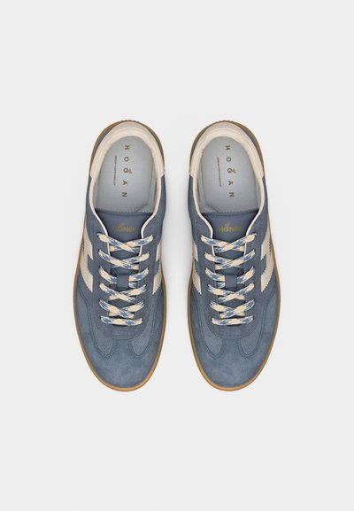 Ζευγάρι μπλε σουέτ αθλητικά παπούτσια με λευκές πλαϊνές ρίγες, κρέμ κορδόνια και σόλες από καουτσούκ, φωτογραφημένα από πάνω σε λευκό φόντο.