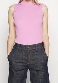 Ribbad rosa ärmlös topp kombinerad med mörk denim vida byxor, med framfickor och kontrasterande sömmar.