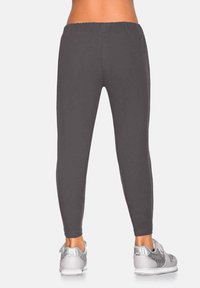 Szare legginsy z elastycznego materiału z elastycznym pasem, dopasowanym krojem i gładką fakturą. W zestawieniu z srebrnymi butami sportowymi.