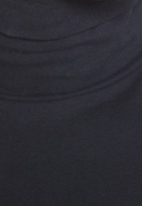 Svart polokrage-top i ett slätt tyg med subtila ribbningar vid kragen och kroppen, med en figursydd design utan synliga mönster eller accenter.