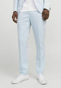 Pantalones de vestir de color azul claro con un ajuste entallado, frente con pliegue y tela suave, combinados con zapatillas blancas para un look casual.