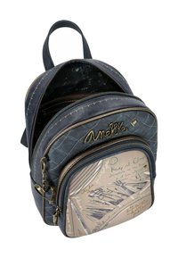 Zaino navy con pattern trapuntato, accessori in oro e una tasca frontale con un design beige che presenta schizzi e testo. Numerosi scomparti con zip.