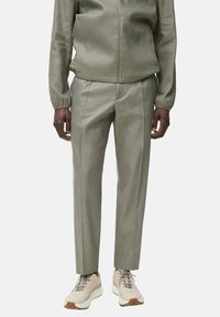 Olivovo zelená mikina so elastickými manžetami, skombinovaná s úzkymi nohavicami v rovnakom odtieni. Doplnkované béžovými teniskami s štruktúrovanou podrážkou.