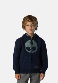 Felpa con zip di colore navy, con un logo circolare e la scritta "NORTH SAILS." Presenta un cappuccio foderato, tasche frontali e un tessuto testurizzato.
