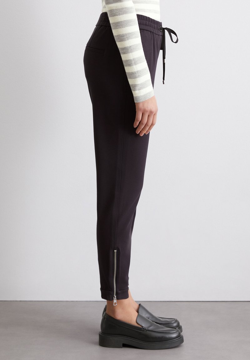 Schwarze Jogginghosen mit elastischem Bund und Kordelzug, ausgestattet mit Seitentaschen und mit Reißverschluss versehenen Knöchelbündchen, aus glattem Stoff gefertigt.