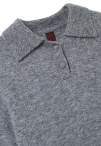 Grau gestricktes Polohemd aus Wolle mit kleinem Kragen, zwei Knöpfen und einem strukturierten Strickmuster. Etikett im Kragen sichtbar.