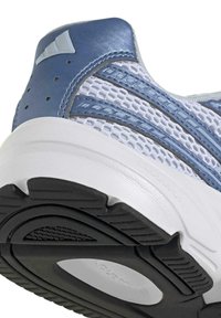 Gros plan sur le talon d'une chaussure de sport avec une tige synthétique bleue, une semelle intermédiaire blanche, un mesh respirant et une semelle extérieure en caoutchouc noir texturé.