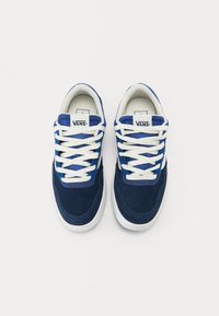 Navy blue suede sneakers with white laces and rubber outsoles. Features a white logo on the tongue and perforations near the toe.