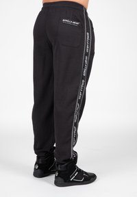 Zwarte gemêleerde sweatpants met zijstrepen en het "GORILLA WEAR" logo, elastische tailleband en achterzakdetail. Gemaakt in combinatie met zwarte schoenen.
