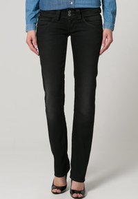 Jeans de mezclilla negra con un ajuste slim, que cuentan con dos bolsillos frontales, dos bolsillos traseros y cierre de botón. Textura suave, detalles de costura sutiles.