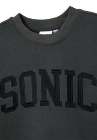 Sudadera gris con cuello redondo acanalado y gran texto bordado en negro "SONIC" en la parte frontal. La tela tiene una textura suave.