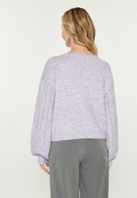 Maglione di un leggero lavanda lavorato a maglia con orlo a coste e maniche puff testurizzate. Il tessuto morbido e i dettagli a punto aperto arricchiscono il design.