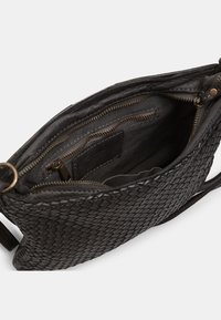Black woven leather handbag with a zipper closure. Interior features multiple compartments and a fabric lining. Adjustable strap included.