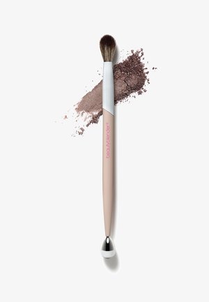 Blending brush with a tapered, soft bristle head. Handle features a beige body with a silver accent and metallic drop-shaped end. Brown powder beside.