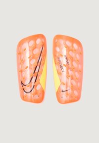 Espinilleras de fútbol naranjas con diseño perforado, con el logo de Nike en negro. Marcadas con "L" y "R" para izquierda y derecha.
