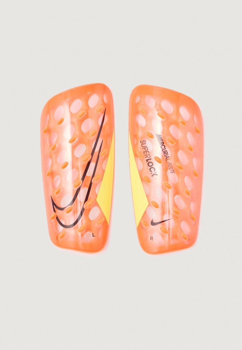 Espinilleras de fútbol naranjas con diseño perforado, con el logo de Nike en negro. Marcadas con "L" y "R" para izquierda y derecha.
