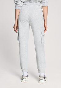 Jasnoszare dresy z elastycznymi mankietami, dwiema bocznymi kieszeniami cargo i miękką fakturą. Zaprojektowane z myślą o komforcie i codziennym noszeniu.