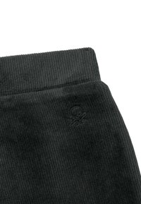 Černá kordurová látka s ribkovanou strukturou a malým vyšitým logem v dolním rohu. Hladký pas s čistým zakončením.