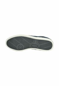 Suola della scarpa con superficie in gomma nera texturizzata, forma curvata e intersuola bianca con un dettaglio del logo circolare.