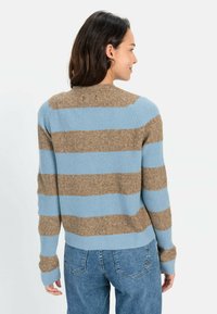 Stripet sweater med vandrette lyseblå og brune striber, ribbet tekstur, rund halsudskæring og lange ærmer. Bæres med blå jeans.