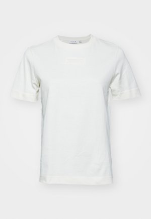 Bela bomba iz 100% bombaža s kratkimi rokavi, okroglim izrezom in teksturiranim logotipom "LACOSTE" spredaj. Gladka tkanina z običajnim krojem.