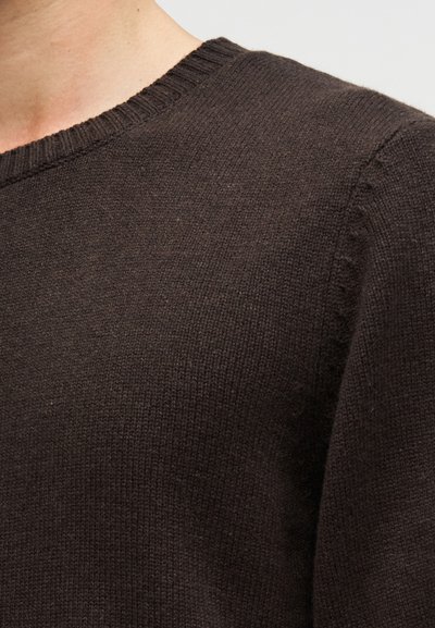 Καφέ πλεκτό πουλόβερ με λαιμόκοψη τύπου crew και ριμπ τελείες, με μαλακή υφή και άνετη εφαρμογή. Κοντινή λήψη λεπτομερειών υφάσματος.