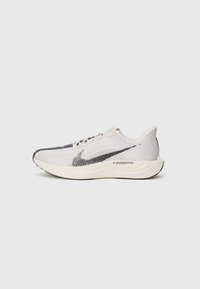 Baskets de course Nike ZoomX gris clair et blanc avec logo swoosh noir et semelle rembourrée, présentées de côté sur un fond uni.