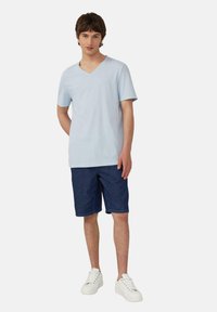 Lichtblauwe T-shirt met korte mouwen en V-hals, gecombineerd met donkerdenimshorts en witte sneakers, met een relaxte pasvorm en klassiek ontwerp.
