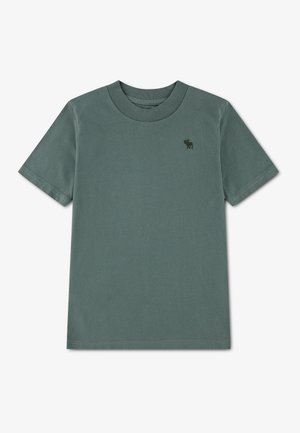 T-shirt uni vert atténué à manches courtes avec petit logo animal sombre sur la poitrine gauche.