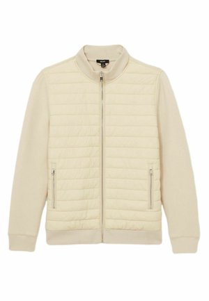 Beige vadderad jacka med slät tygt, ståkrage, framsidans dragkedja och två sidofickor. Har ribbade mudd och nederkant.