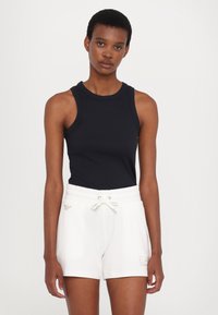 Camiseta sin mangas negra combinada con pantalones cortos blancos de cintura elástica que cuentan con cordón y detalle de logo bordado.