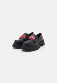 Black leather slip-on shoes with a thick, ridged sole, featuring red lips graphic accents on the front. Smooth texture, modern design.