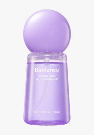 Paarse doorschijnende fles met een afgeronde dop, gelabeld "Biodance Caviar PDRN Jelly Serum Mist", met 50 ml product.