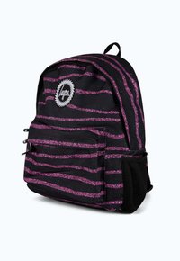 Musta reppu, jossa on vaaleanpunaiset glitteriviivat. Siinä on vetoketjullinen etutasku, verkkosivutasku ja pyöreä logo-ompelus edessä.