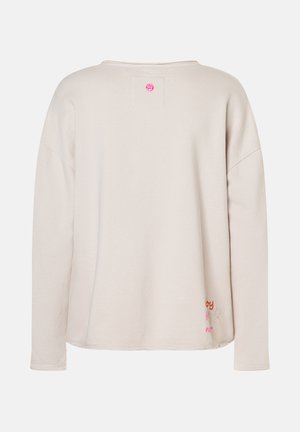 Beige Sweatshirt mit langen Ärmeln und lockerer Passform, kleinem rosa Rundlogo am Hals und buntem gesticktem Text sowie Herz am unteren Saum.