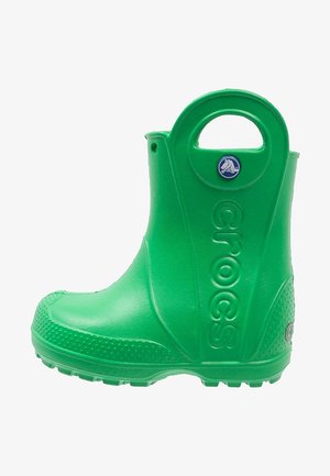 Bota de goma verde con diseño redondeado, superficie texturizada y asa circular recortada. Presenta la marca "crocs" en el lateral y una suela elevada.