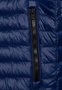 Navy blue puffer jacket featuring a black zipper along the front, with quilted texture and horizontal stitching detail.