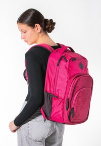 Zaino rosa con finitura testurizzata, compartimenti a doppia zip, spallacci ergonomici e tasca laterale in rete per ulteriore spazio di stoccaggio.