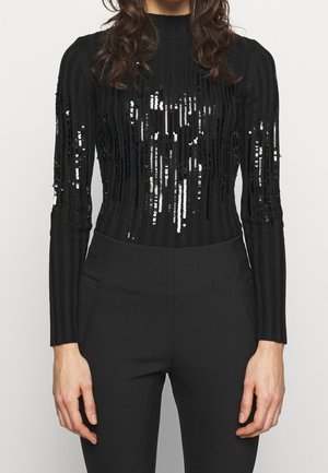 Black long-sleeve top with vertical stripes and sequins. Features a fitted silhouette and high neckline, paired with sleek black pants.