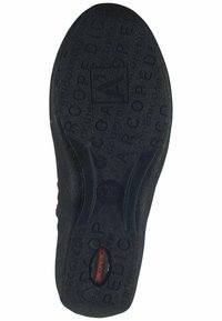 Suela de zapato de goma negra con una superficie texturizada y marca en relieve. Bordes curvados y un detalle circular central para tracción.