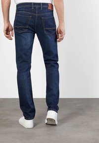 Dark blue denim jeans with a straight fit, featuring two back pockets, contrast stitching, and a brown leather waistband accent.